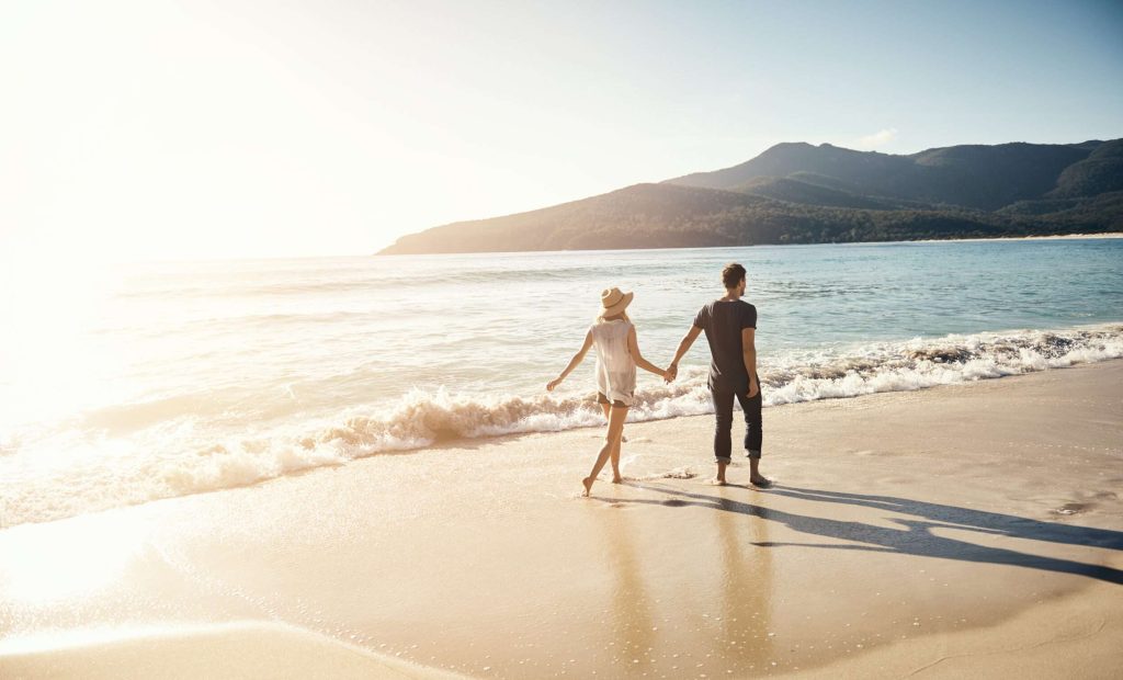 Shot of a young couple going for a stroll along the beach
